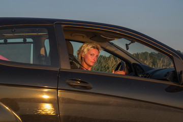 beautiful woman in the car and the glare of the sunset