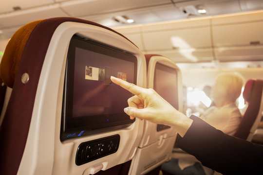 Hand touching LCD at the entertainment screen in a plane
