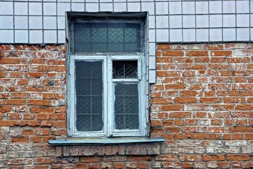 Старая окно с решёткой на кирпичной стене дома