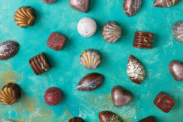 Colored chocolate candies. Creative sweets on a turquoise background.