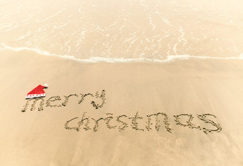 Merry Christmas written on tropical beach white sand with xmas hat