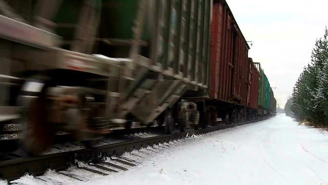 Commodity train moves in the winter woods. A multi-train rushes along the rails shrouded in snow. Trains with tank cars of oil and gas on the North road. Rail commodity movement.  