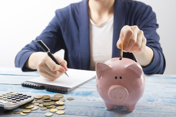 Hand putting coin into piggy bank closeup. selective focus