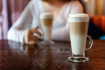 Latte macchiato in tall glass close up. Coffee on a table in cafe