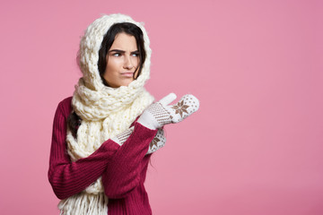 a woman in a pink dress, mittens and a white scarf on her head frowns, a light pink background, free space for copying, a holiday, a new year