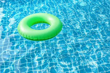 Green pool float, ring floating in a refreshing blue swimming pool