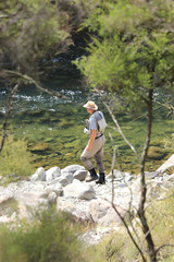 Fly fisherman walking on rocky bank of New Zealand river