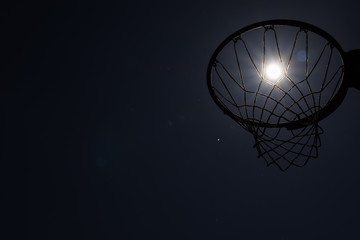 Looking up through silhouetted basketball goal to the moon at night © Jeremy