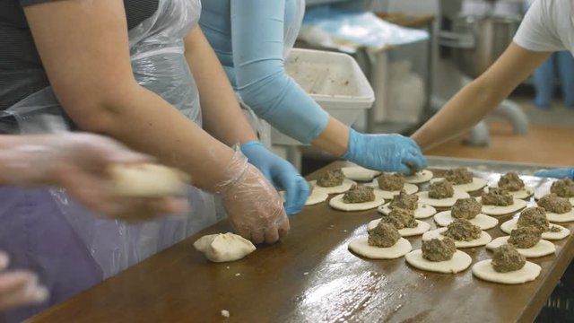Bakers lay raw minced meat in the each of piece of dough