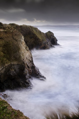 Fototapeta na wymiar a beautiful long exposure of the waves crashing against the north cliff of Gwithian beach, Cornwall, England