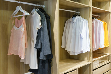 modern wooden wardrobe with clothes hanging on rail in walk in closet design interior