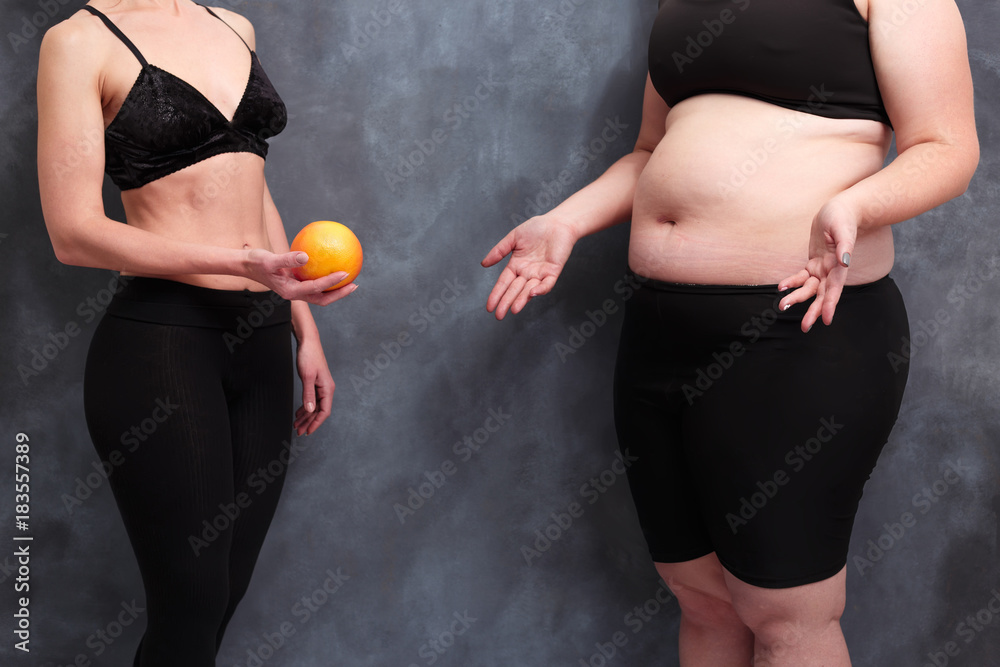 Wall mural fit woman offering grapefruit to overweight lady. extreme diet, starving, harm, healthcare, weight l