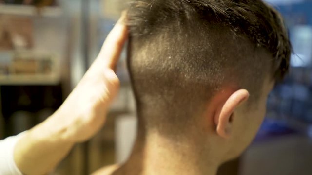 Closeup of teenage boy using a trimmer to cut his hair very short on the back of his head.