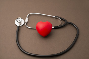 Red Rubber Heart and Stethoscope on Brown Background