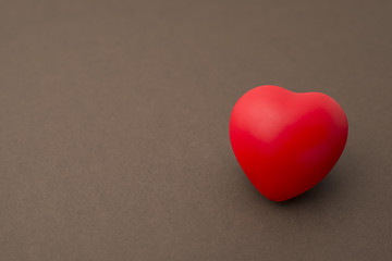 Lone Red Rubber Heart on a Brown Background Copy Space