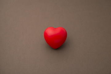 Single Red Rubber or 3D Heart Isolated on Brown Background