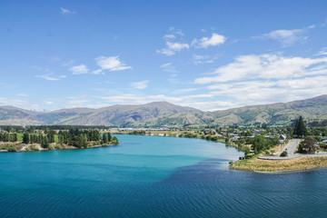 clear blue Tekapo lake with tall pine and mountain range