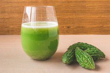 Herbal juice with bitter melon or bitter gourd on wooden background.