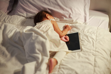 baby sleeping on bed after playing tablet