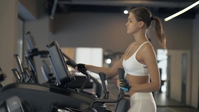 Sports woman training cardio exercise on cross trainer in fitness clube