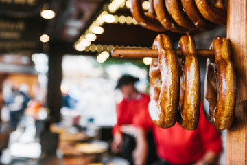 Traditional pretzels called Brezel hang on the stand against the background of a blurred street...