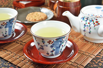Japanese green tea and teapot on bamboo mat