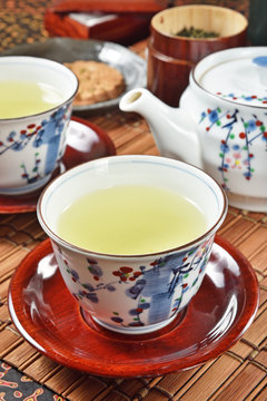 Japanese green tea and teapot on bamboo mat