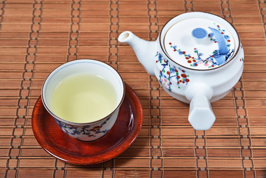 Japanese green tea and teapot on bamboo mat