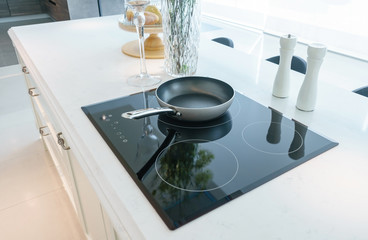 Frying pan on modern black induction stove, cooker, hob or built in cooktop with ceramic top in...