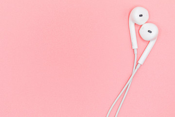 Top view Lovely Closeup of White Earphones on Pink Pastel plastic texture background. Pastel color concept, Minimal concept. Copy space. Music is my life concept. Valentine concept