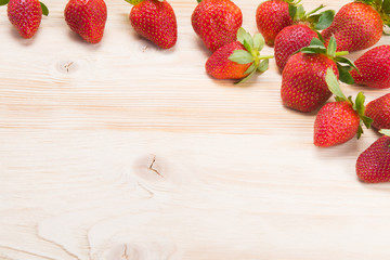 on a light wooden board in the right corner, a red strawberry, on the background there is a place for an inscription