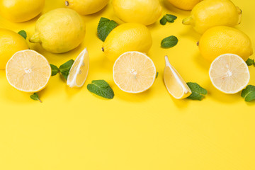 on a yellow table laid out lemons, for a background, with green branches, from below there is a place for an inscription
