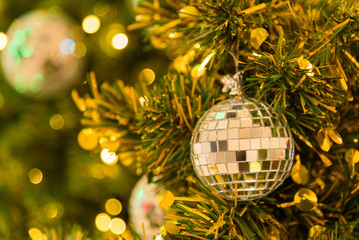 Many mirror balls decorate on green leaves tree and lighting system in a department store in greeting season such as Christmas and New Year festival.Bokeh light backgrounds in Christmas.