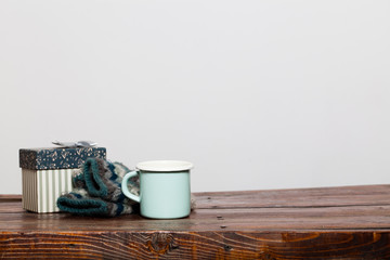 vintage bright green cup with hot tea and warm gloves on wooden table