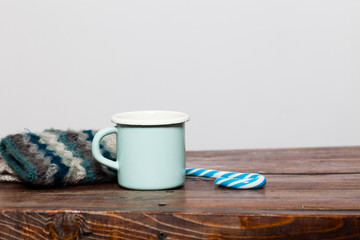 vintage bright green cup with hot tea and warm gloves on wooden table