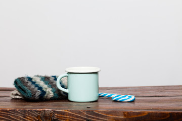 vintage bright green cup with hot tea and warm gloves on wooden table