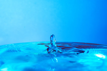 drop of water falling in blue water and blue background.