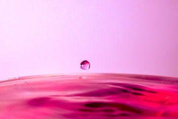 drop of water falling in red water and red background.