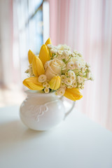 Romantic bouquet of yellow tulips and white roses in white porcelain jug
