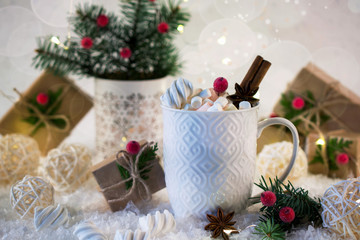 Hot chocolate in a white cup with marshmallows and Christmas gifts on the bright light background. Christmas drink.