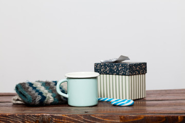vintage bright green cup with hot tea and warm gloves on wooden table