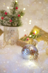 Fototapeta na wymiar New Year's decoration ball on snow background with presents. Christmas card