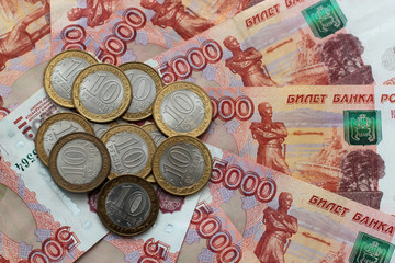 Russian money of five thousands denominations and commemorative coins lie on the table mixed