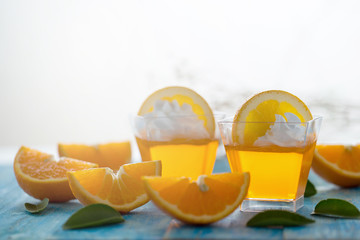 Orange jelly in a cup with whipped cream and orange sliced on blue wooden  background