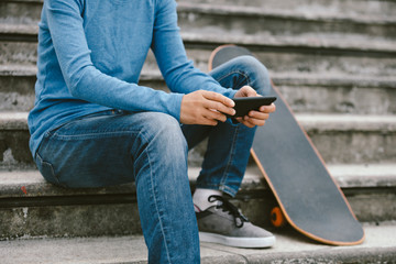 skateboarder use smartphone sit on city stairs