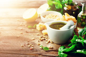 Ingredients for homemade pesto - basil, lemon, parmesan, pine nuts, garlic, olive oil and salt on rustic wooden background. Top view, flat lay, copyspace. Banner
