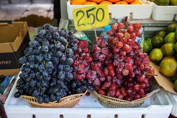 Fruit baskets of fresh sweet black and red grapes selling in local market with price tag