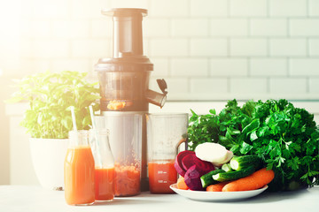 Woman making fresh drink. Juicer and carrot juice. Fruits in background. Clean eating, detox concept