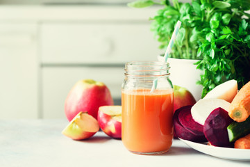 Woman making fresh drink. Juicer and carrot juice. Fruits in background. Clean eating, detox concept