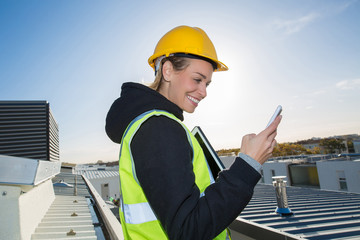 female worker on construction site using tablet pc and mobile phone